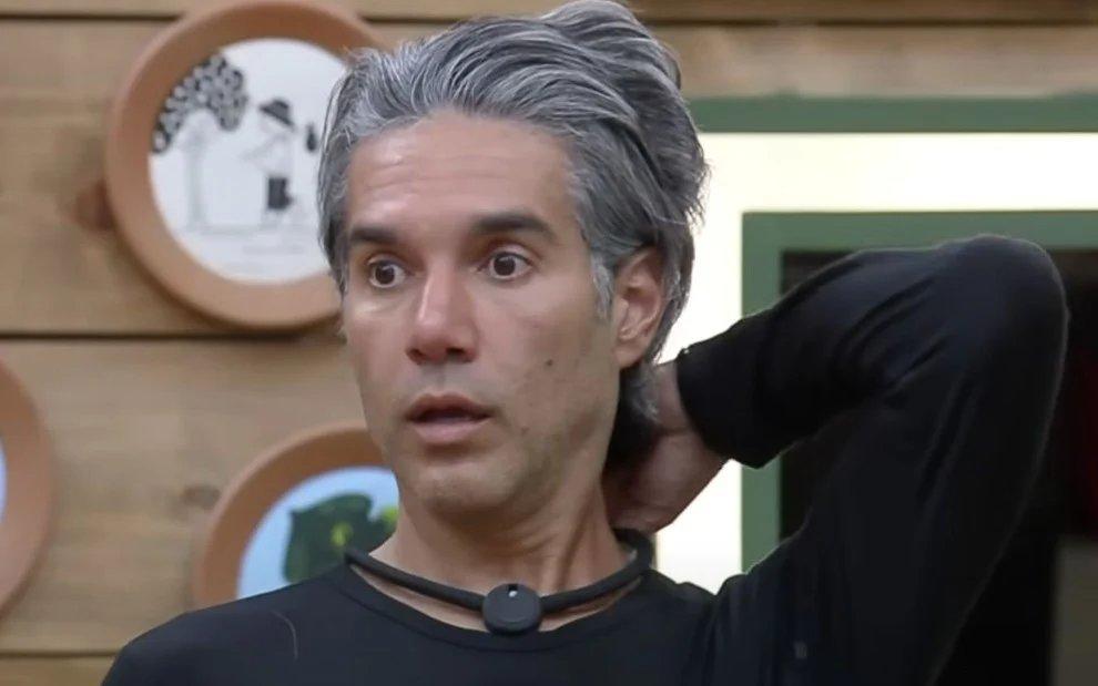 Fernando Sampaio em A Fazenda. Ele está de blusão preto e com o microfone da fazenda.