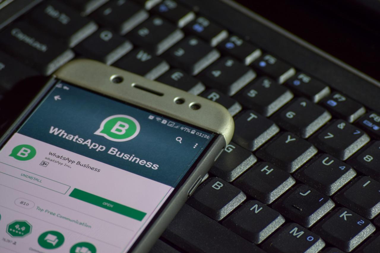Smartphone com aplicativo WhatsApp Business ligado em cima de um teclado de computador.
