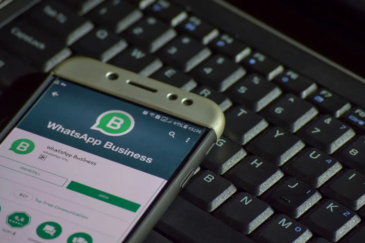 Smartphone com aplicativo WhatsApp Business ligado em cima de um teclado de computador.