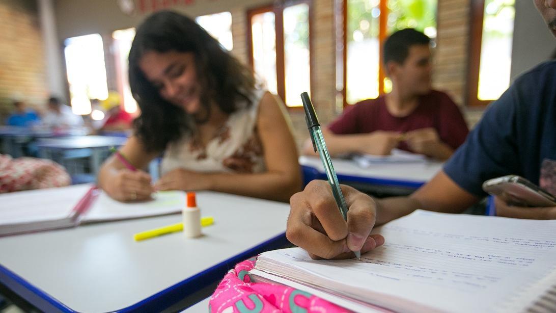 Crianças em sala de aula com lápis e caderno na mão