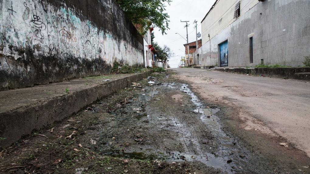 Rua de Fortaleza com falta de esgotamento sanitário e rachaduras na pavimentação.