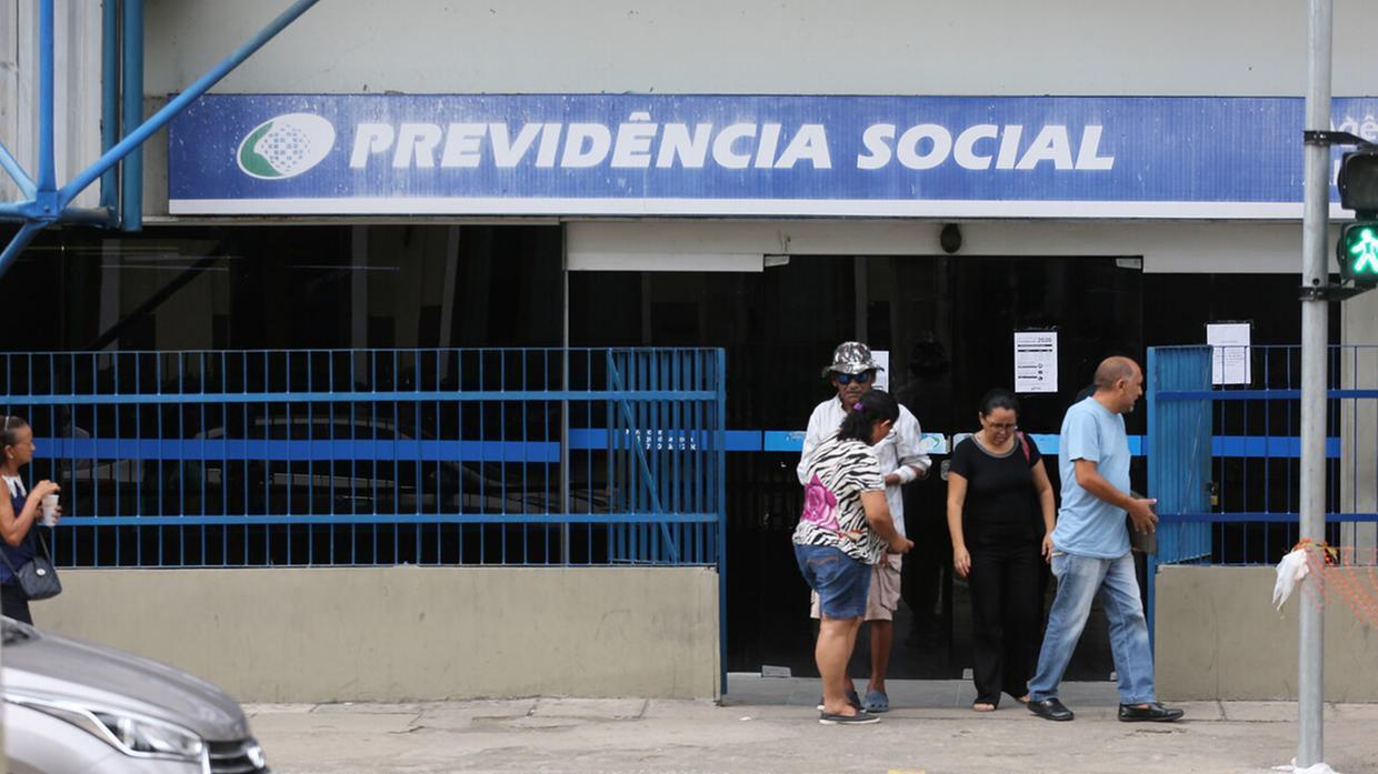 Pessoas saem de agência da Previdência Social em Fortaleza, representando o atendimento e as filas do INSS no Ceará.