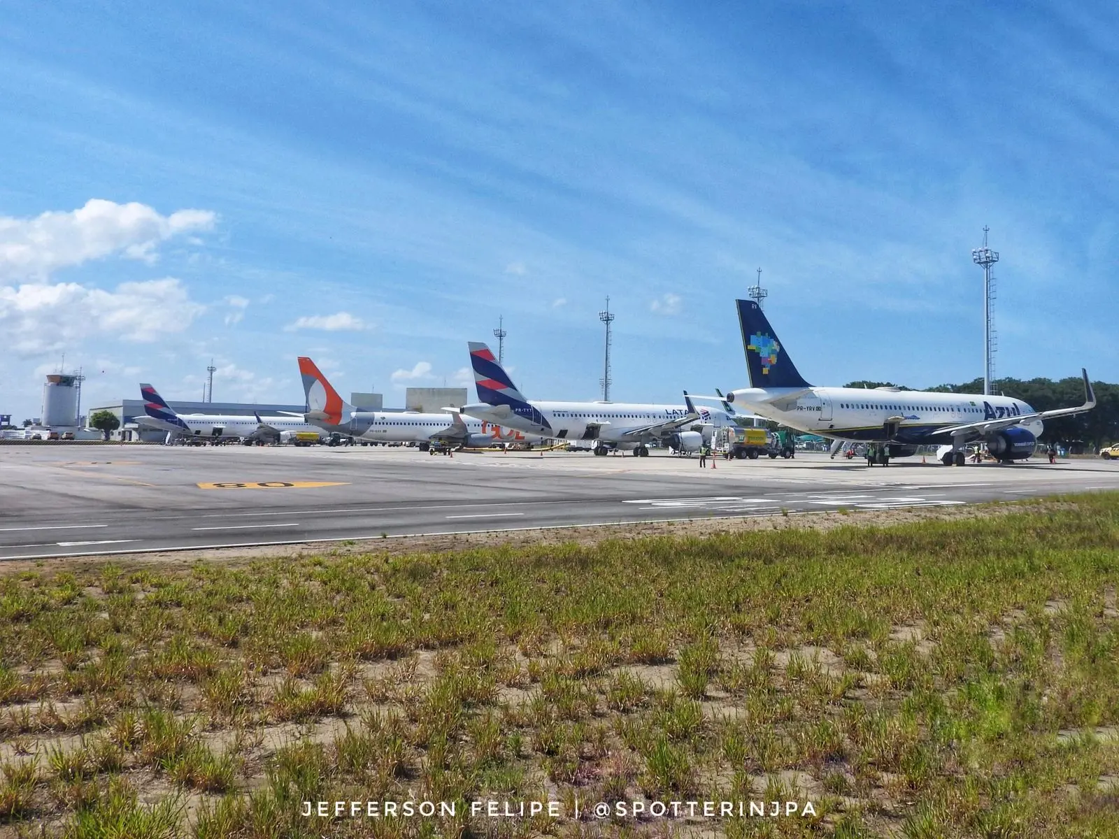 Fachada moderna do Aeroporto Internacional de Natal, administrado pela Zurich Airport Brasil, com estrutura de vidro e cobertura metálica curva sob céu azul.