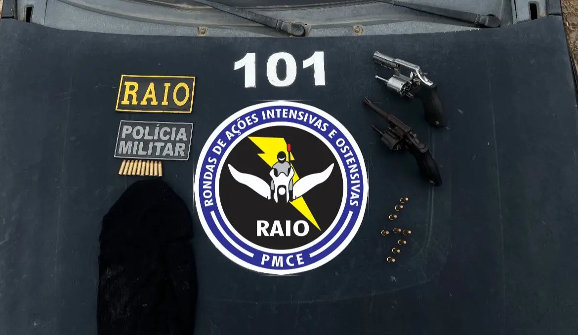 Armas apreendidas pela Polícia Militar dispostas sobre mesa com o emblema do Raio.