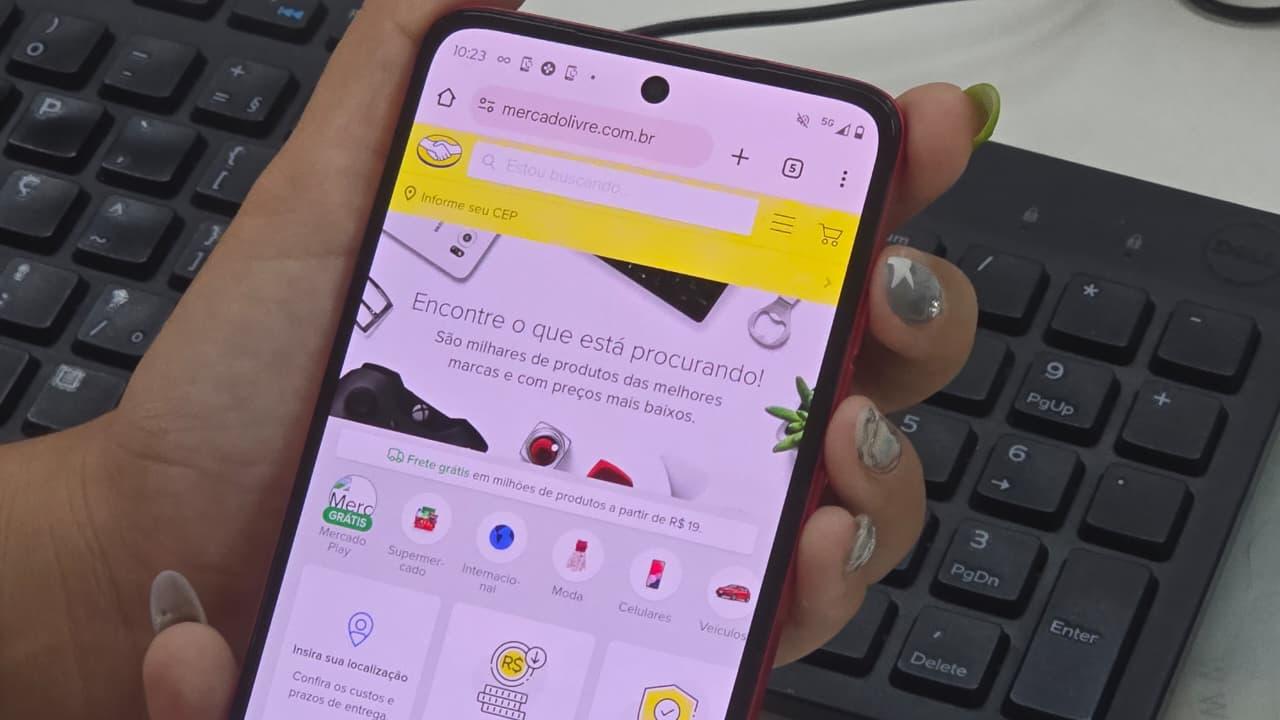 Mão segurando um smartphone com a tela do Mercado Livre aberta