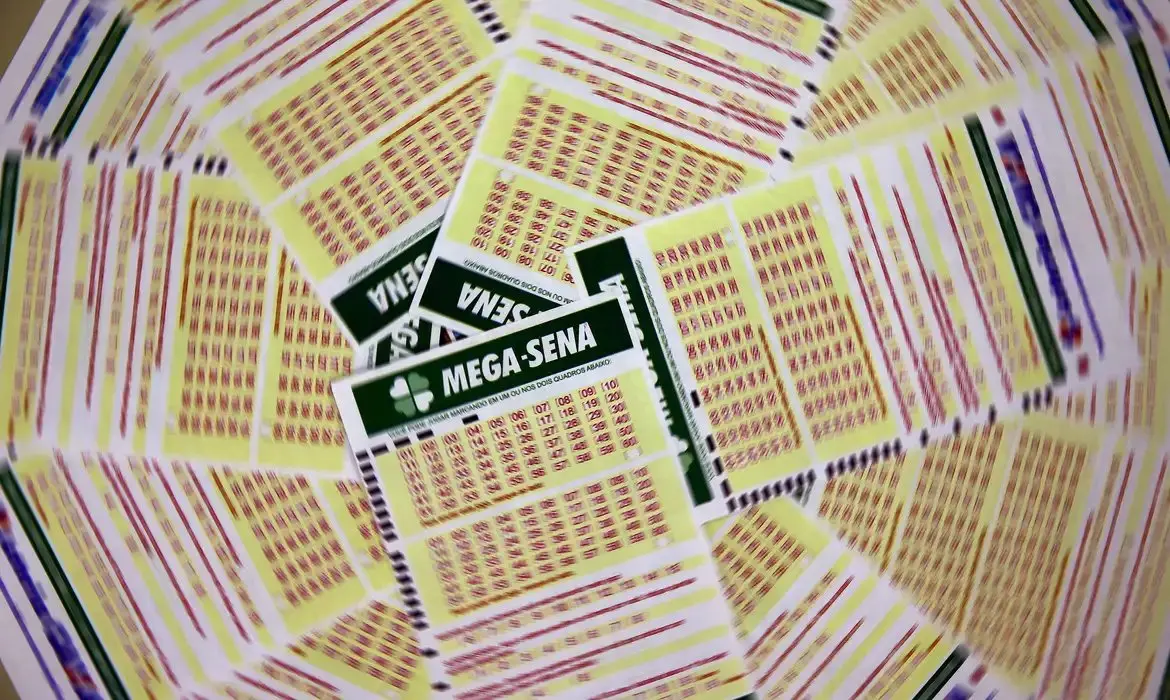 Lote de bilhetes da Mega-Sena com detalhes em cores variadas, destaque para o logo da loteria, em uma mesa, prontos para jogar e participar do sorteio.