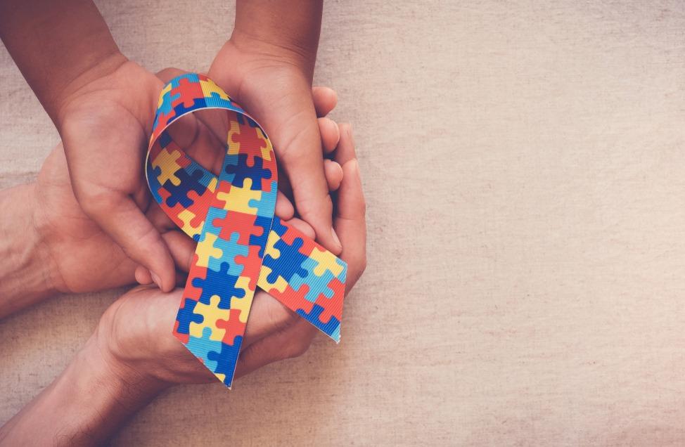 Mãos segurando fita quebra-cabeça para o Dia Mundial da Consciência do Autismo.