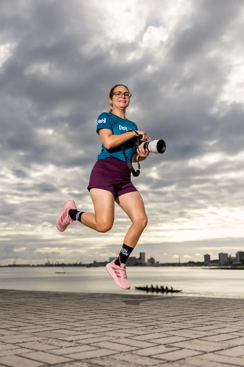 Fotógrafa mulher faz pose em pulo.