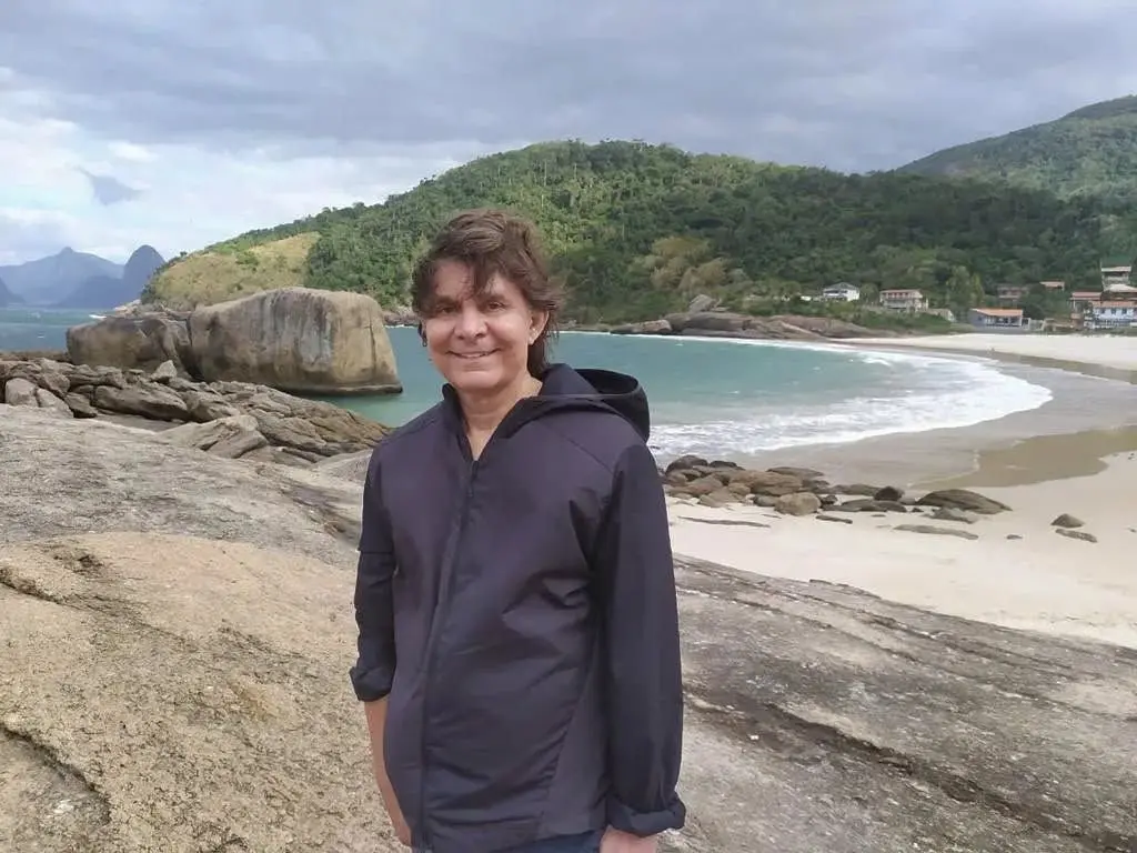 Lô Borges posando diante de paisagem de praia. ainda não tem previsão de alta.