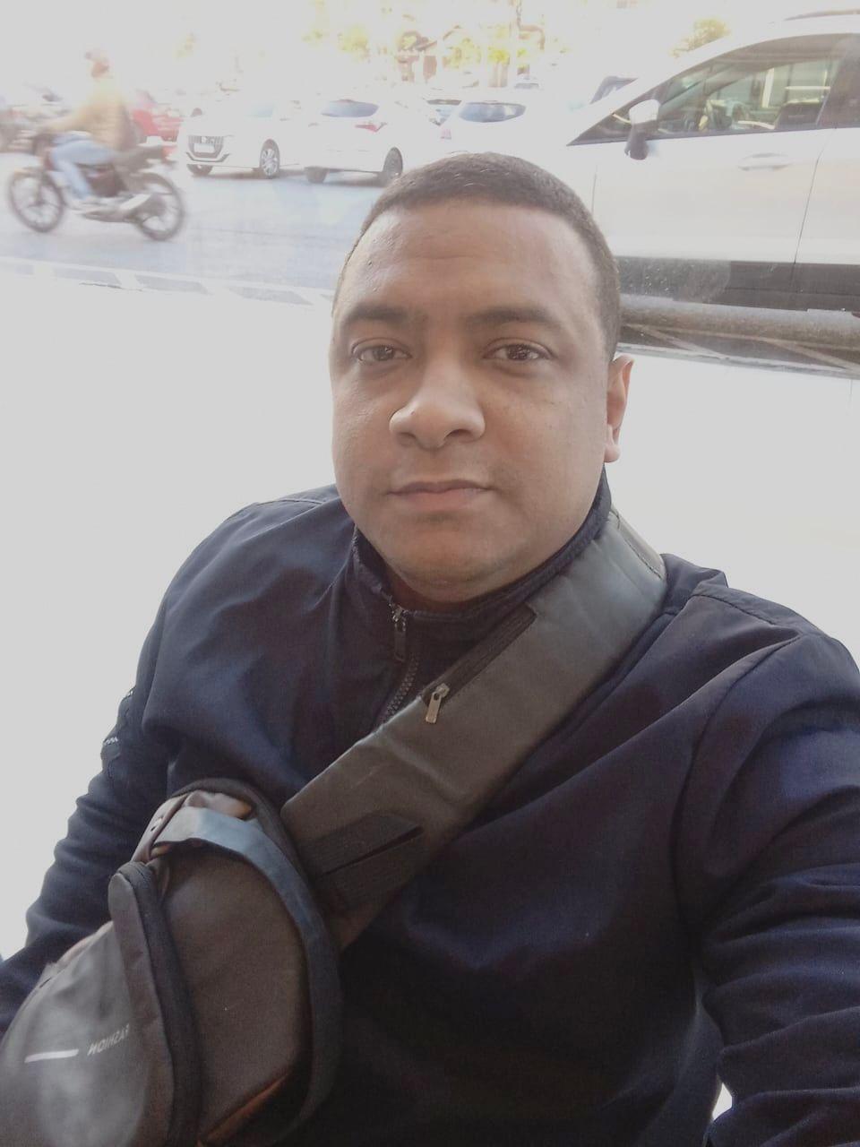 Foto de vigilante cearense que morreu em acidente em Santa Catarina. Na foto ele está de casaco azul-marinho e com bolsa atravessada no corpo.