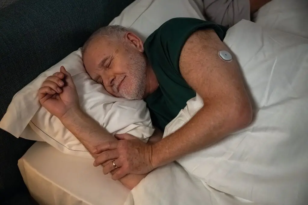 Imagem de um homem diabético dormindo com sensor no braço para matéria sobre novo sensor de glicemia usa inteligência artificial para prever quedas de açúcar.