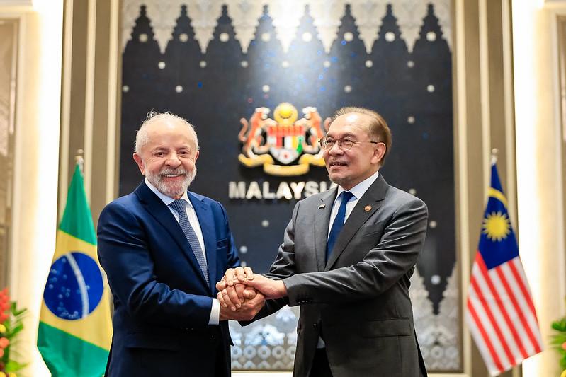 Foto do presidente da República do Brasil, Luiz Inácio Lula da Silva, durante reunião restrita com o Primeiro-Ministro da Malásia, Anwar Ibrahimi, no Palácio de Governo. Ambos homens idosos, aparecem na foto segurando as mãos um do outro.