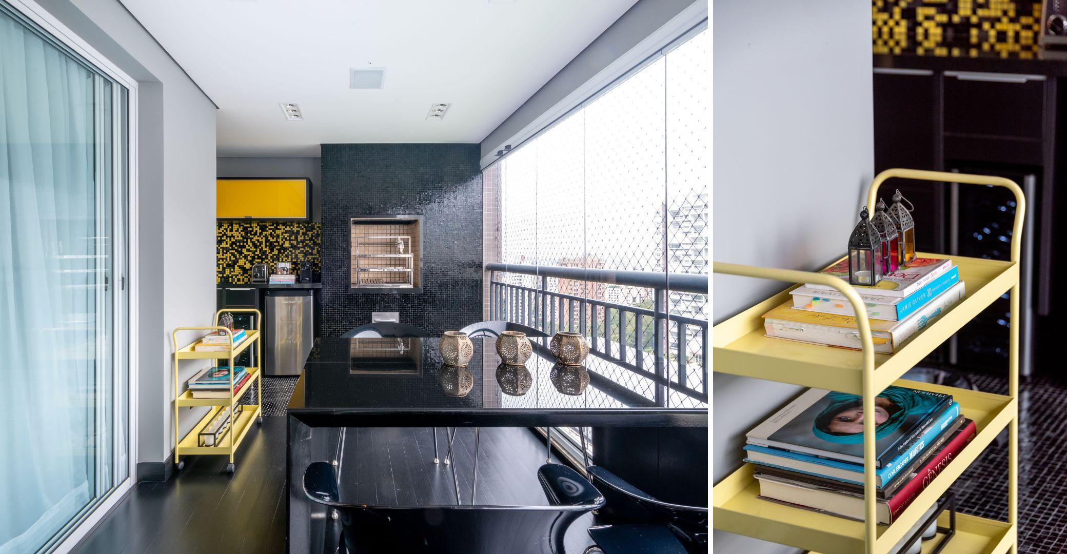 Varanda moderna com mesa de vidro, cadeiras pretas, prateleira amarela com livros e decoração, vista para cidade.