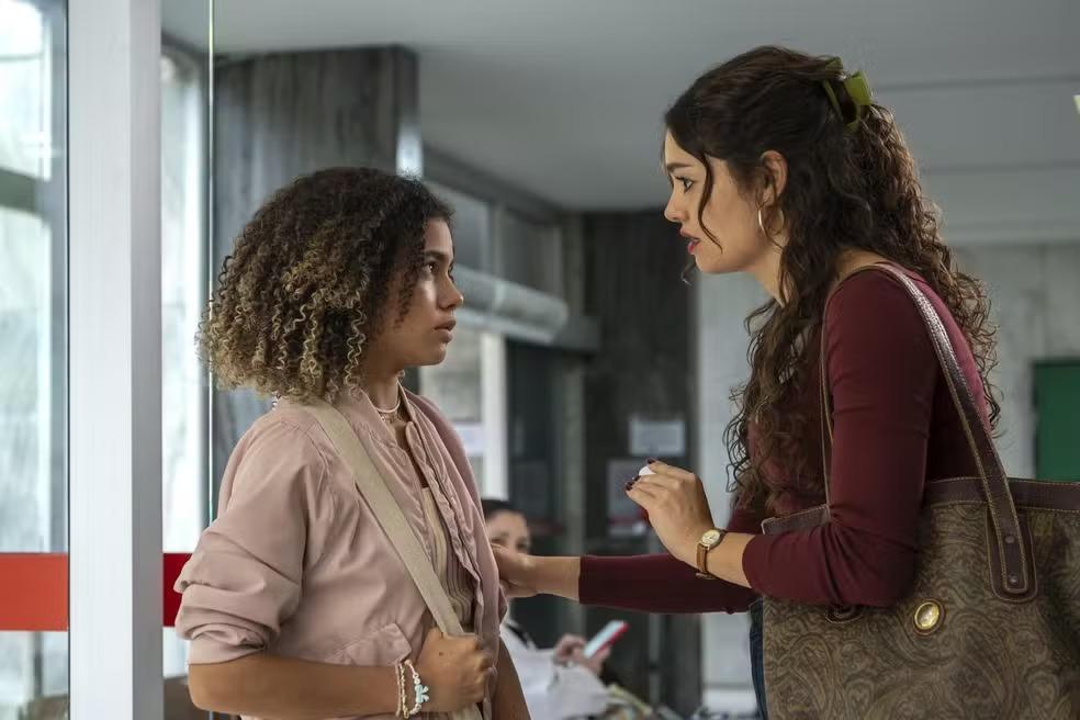 Alana Cabral à esquerda, caracterizada como Joélly, e Sophie Charlotte à direita, como Gerluce. As duas estão conversando seriamente.