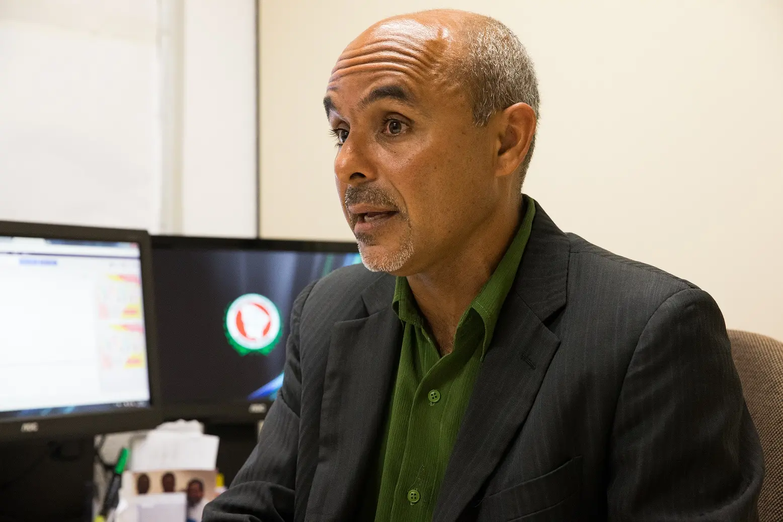 Promotor de Justiça Dairton Oliveira, um homem calvo, de cavanhaque e terno em sala com computador.