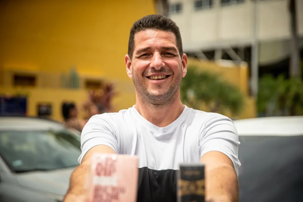 imagem de homem sorridente segurando duas embalagens de perfumes.
