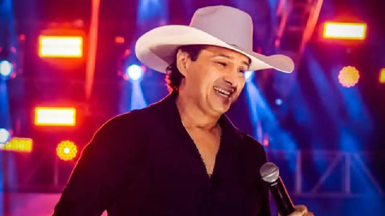 Imagem mostra Vicente Nery com microfone em uma mão, usando chapéu e cantando.