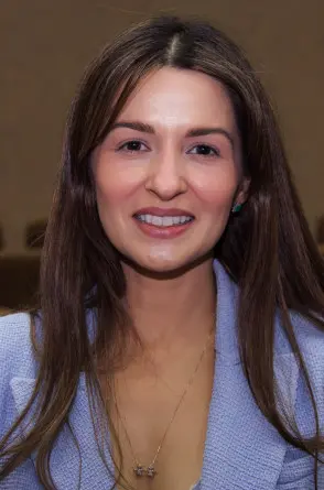 Juíza Giselli Lima, uma mulher branca de cabelos castanhos e lisos e terno lilás.