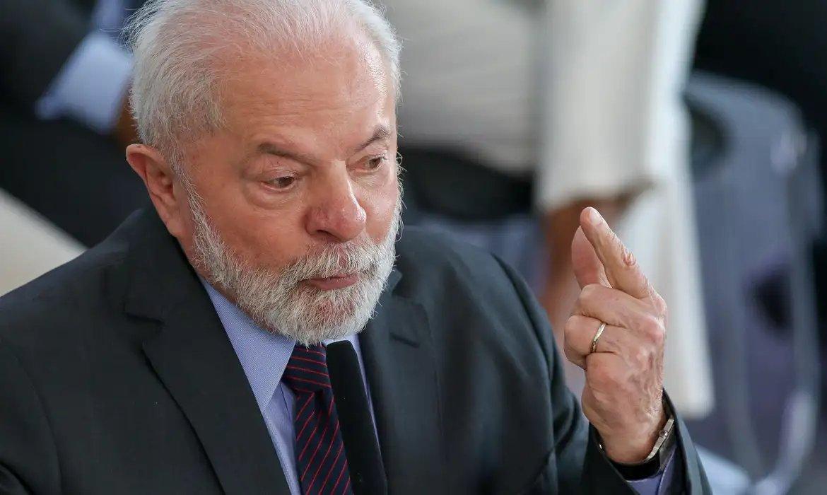 Imagem do presidente do Brasil, Lula, com expressão séria e concentrada, gesticulando para fazer um ponto.
