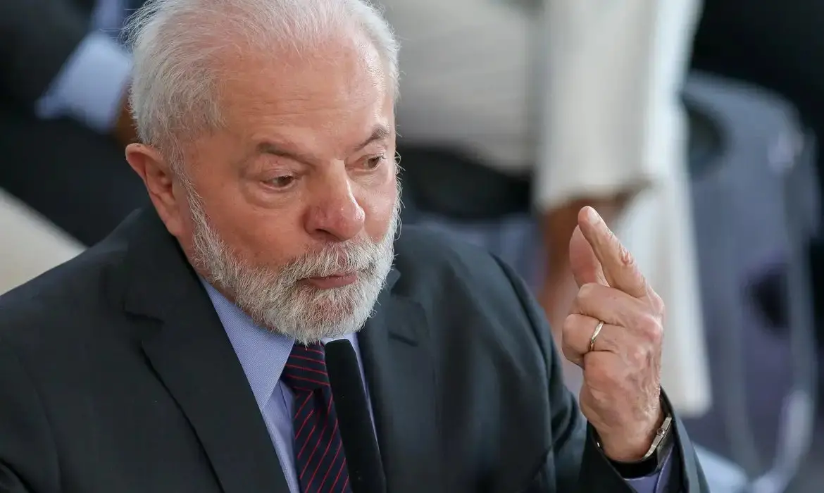 Imagem do presidente do Brasil, Lula, com expressão séria e concentrada, gesticulando para fazer um ponto.