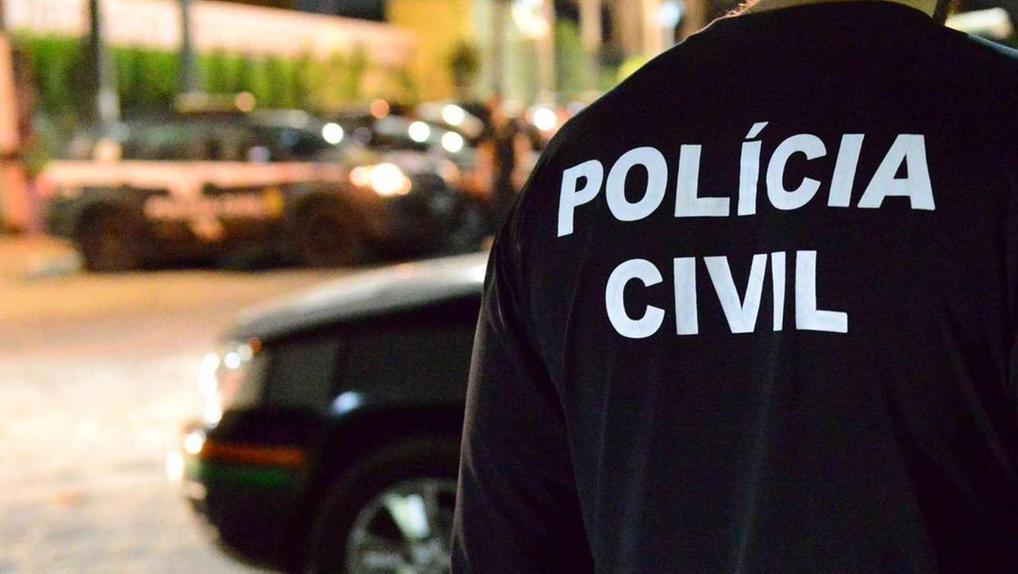 Policía Civil em ação, agente policial de costas com uniforme preto, na rua, com veículos ao fundo, representando a força policial do Ceará.