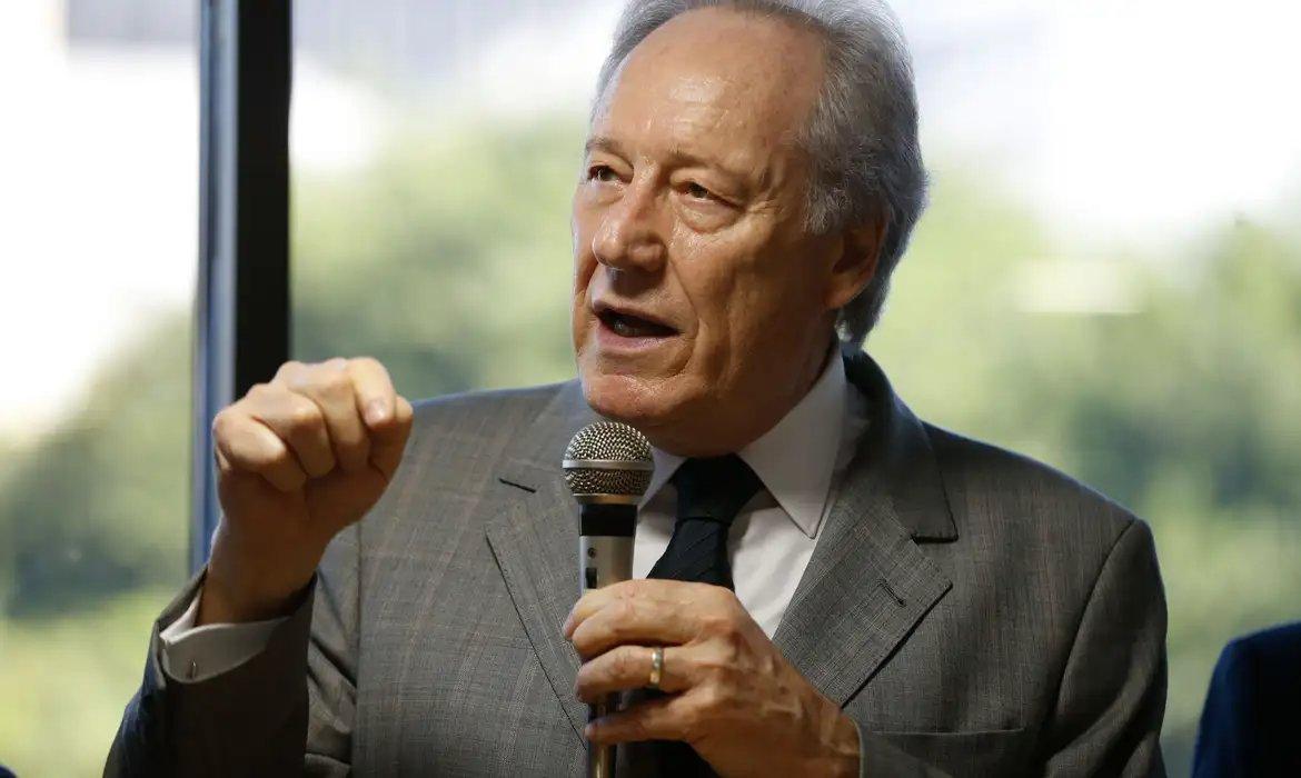 Imagem mostra o ministro da Justiça, Ricardo Lewandowski, com expressão séria gesticula com a mão esquerda fechada enquanto fala em um microfone, em um cenário de escritório.