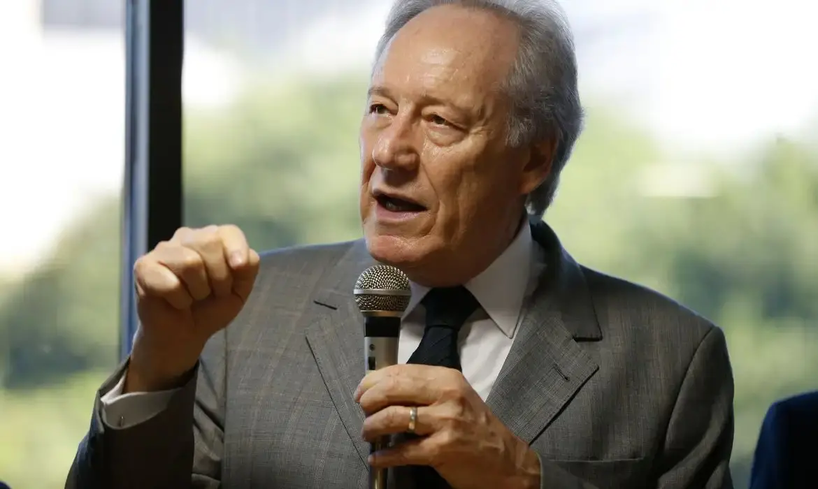 Imagem mostra o ministro da Justiça, Ricardo Lewandowski, com expressão séria gesticula com a mão esquerda fechada enquanto fala em um microfone, em um cenário de escritório.