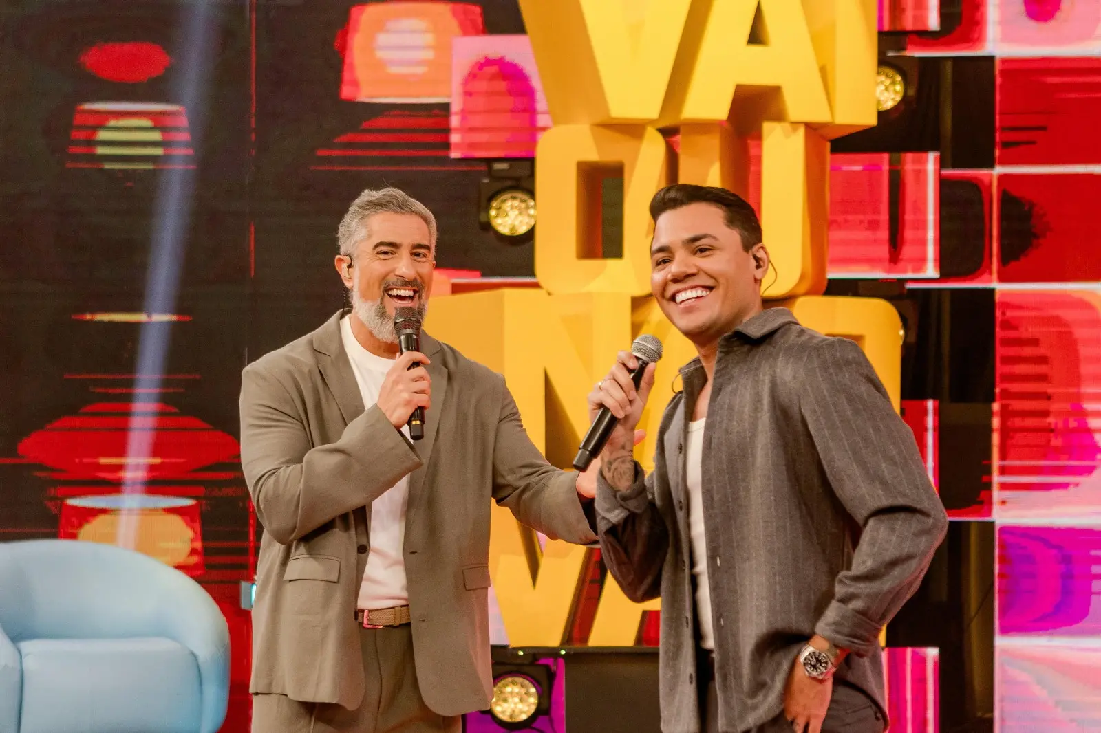 Cristiano Araújo e Marcos Mion em momento descontraído, ambos segurando microfone.