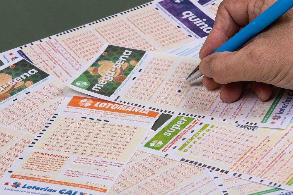 Foto de da mão de um pessoa preenchendo um bilhete da Loteria Federal Caixa Econômica.