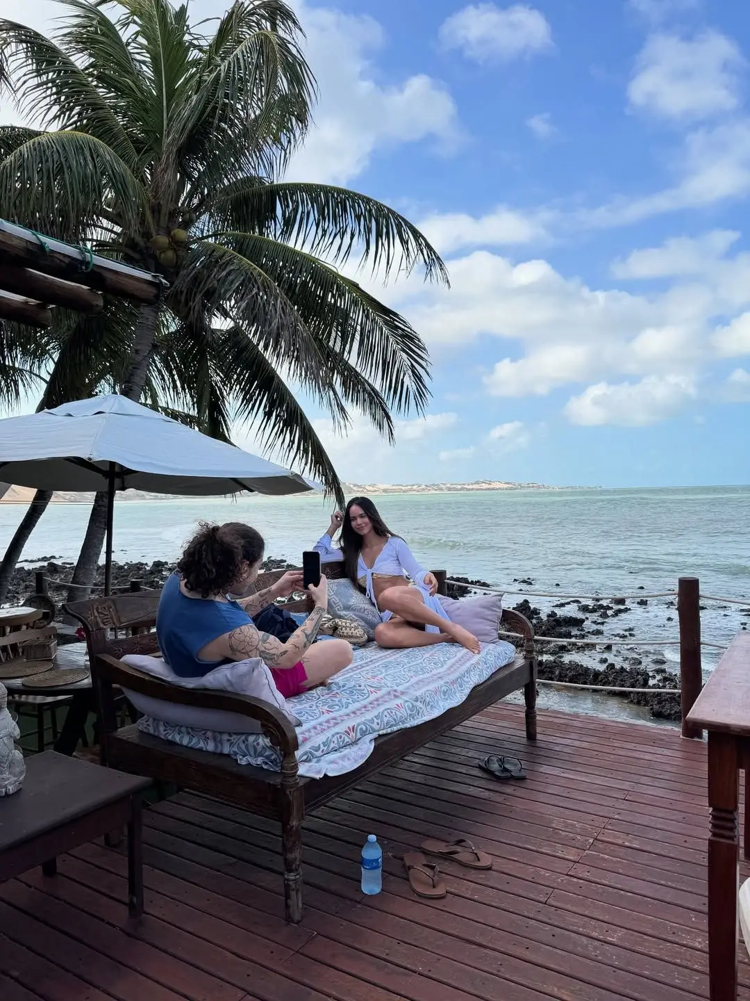Whindersson fotografando Yasmin em um soffá na praia.