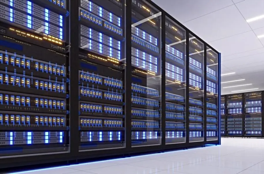 Foto de uma central de computadores dentro de um data center. São grandes equipamentos marcados por fios de conexão e luzes amarelas e azuis.