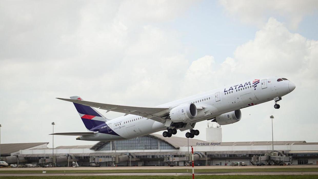 Aeronave da Latam levantando voo, ao fundo aparecer o aeroporto de Fortaleza.