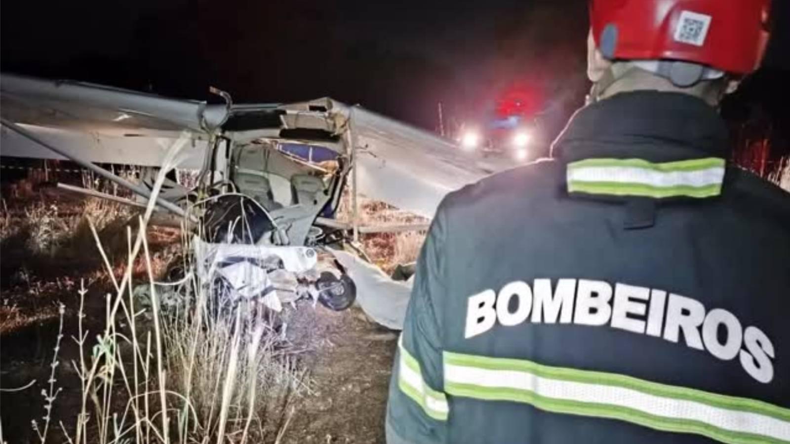 Imagem mostra bombeiro em cena noturna de acidente aéreo, registrado em Tocantins, com destroços de um avião de pequeno porte visíveis ao fundo.