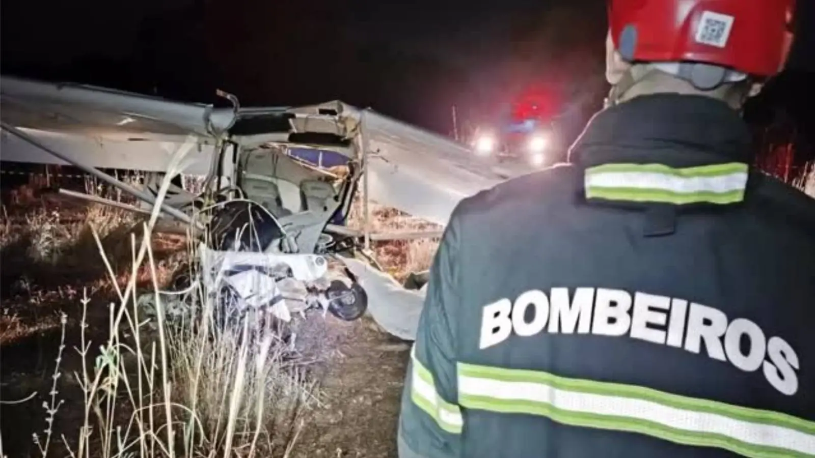 Imagem mostra bombeiro em cena noturna de acidente aéreo, registrado em Tocantins, com destroços de um avião de pequeno porte visíveis ao fundo.