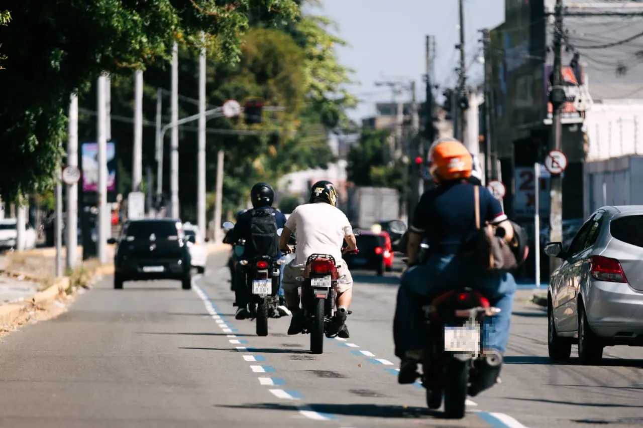 Motociclistas trafegam por faixa azul na avenida Humberto Monte, em Fortaleza.