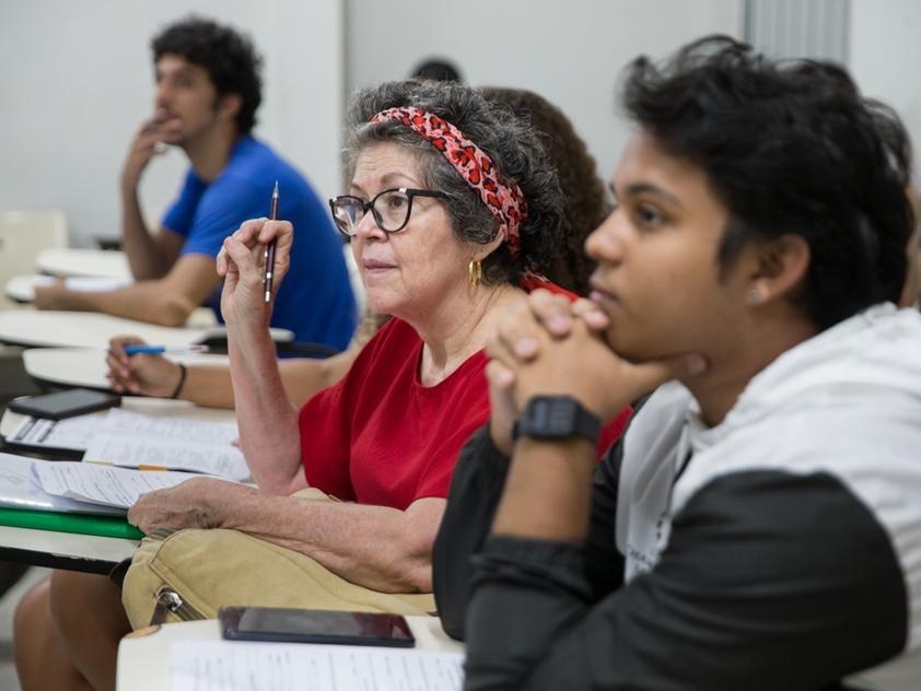 Idosa em sala de aula com jovens.