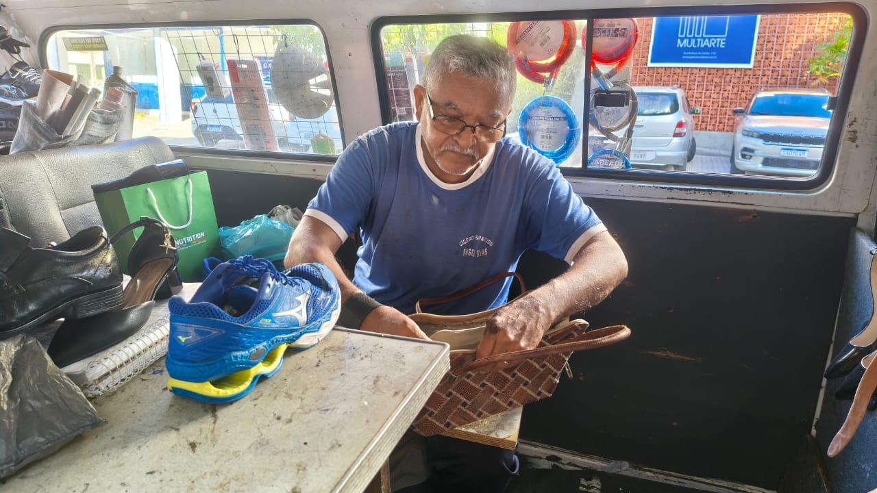 Homem exercendo o ofício de sapateiro dentro de uma kombi.