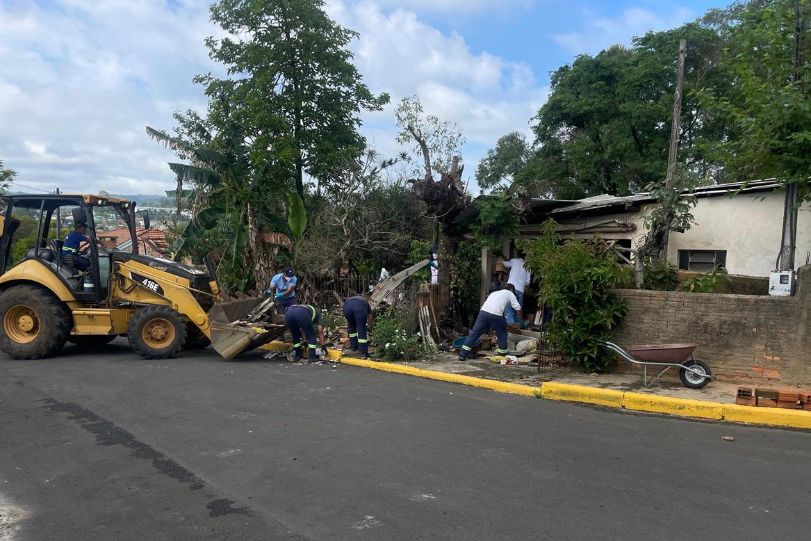 Limpeza da vigilância sanitária junto com os detentos. na imagem, uma retroescavadeira está diante de uma casa com bastante entulho. no local, detenta encontrou 8,1 mil reais.