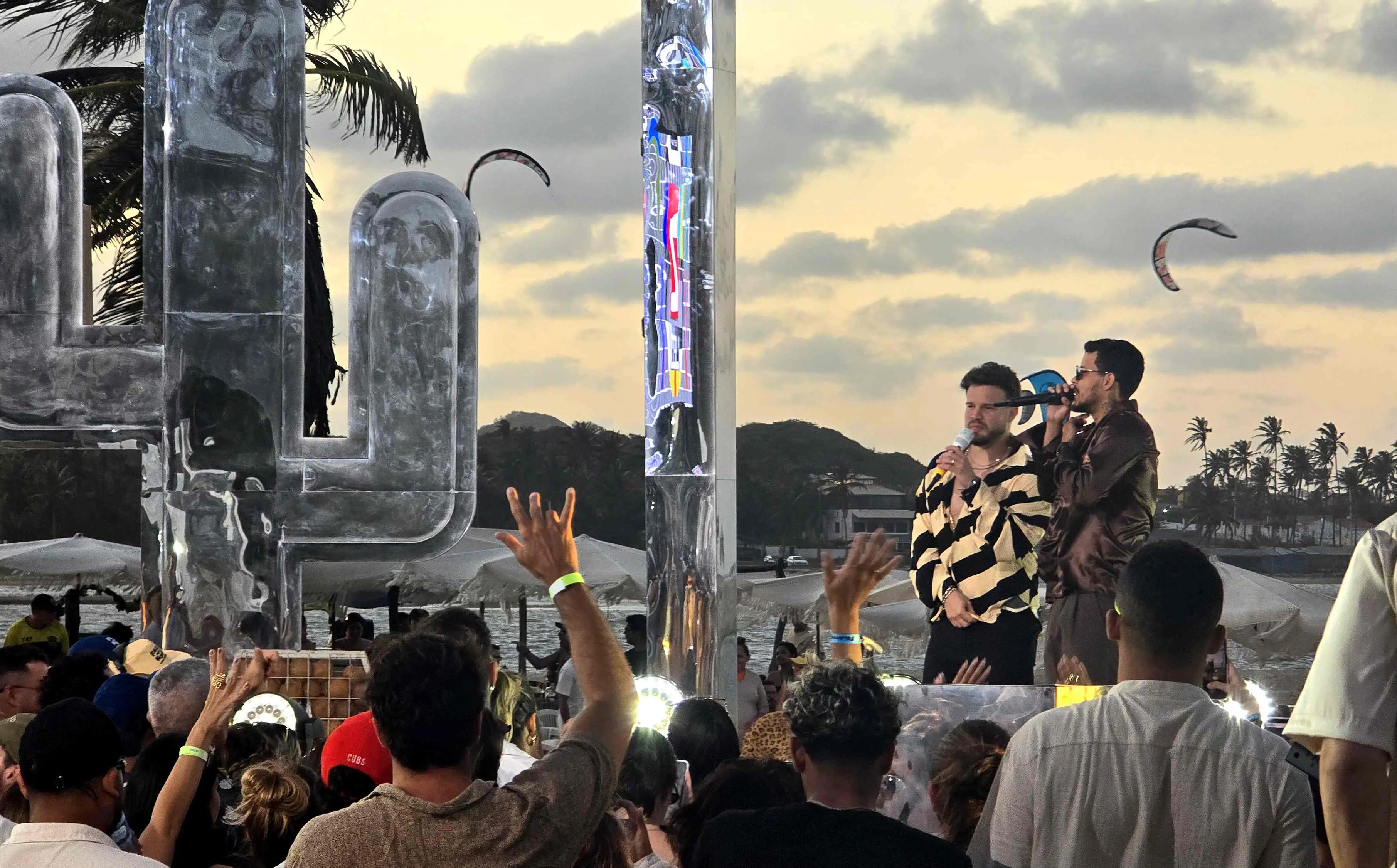 Matheus Fernandes ao lado de Felipe Amorim em DVD gravado no Cumbuco. Um grande cacto feito de metal aparece ao fundo. E o público aparece na frente do palco.
