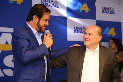 Antônio Rueda está em pé ao lado de Roberto Cláudio. O dirigente partidário está em um salão cheio de espectadores durante evento de filiação do ex-prefeito de Fortaleza ao partido. Rueda veste uma camisa azul clara com um blazer azul escuro por cima, segura um microfone e olha para Roberto Cláudio.