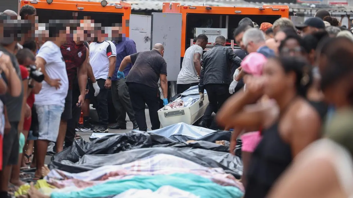 Dezenas de corpos de pessoas mortas durante operação policial no Rio de Janeiro são levados em carros do IML para serem identificados sob o olhar de pessoas da comunidade do Complexo do Alemão.