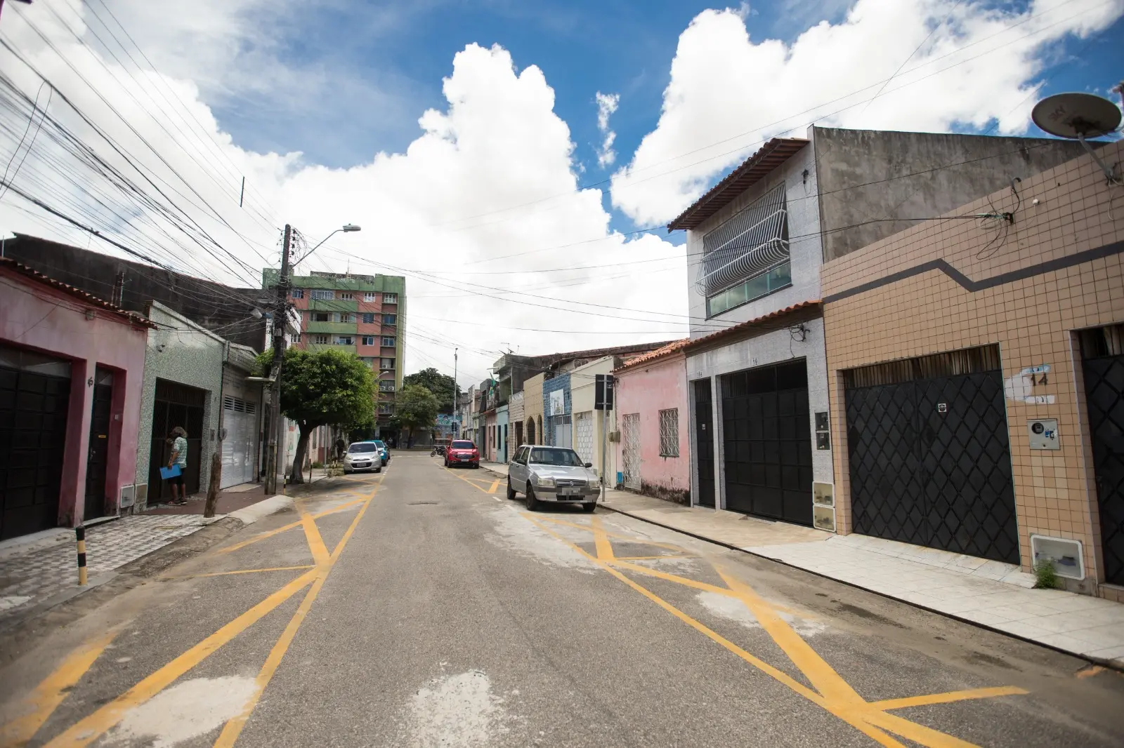 Imagem mostra rua tranquila do Centro de Fortaleza, com alguns carros estacionados e casas em ambos os lados. Acima, um céu azul com nuvens brancas.