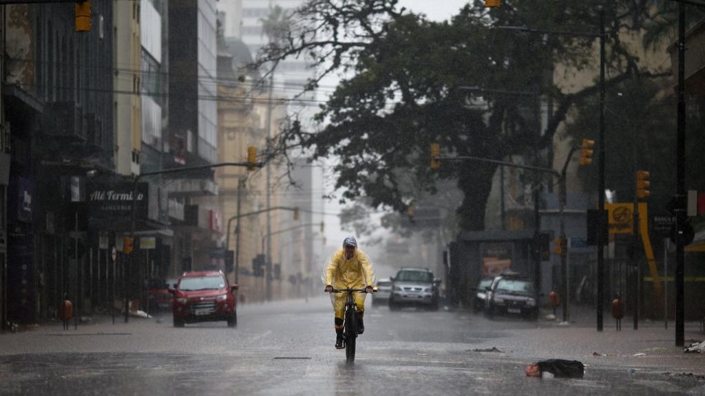 Homem anda de bicicleta sob chuva em Porto Alegre, Rio Grande do Sul.