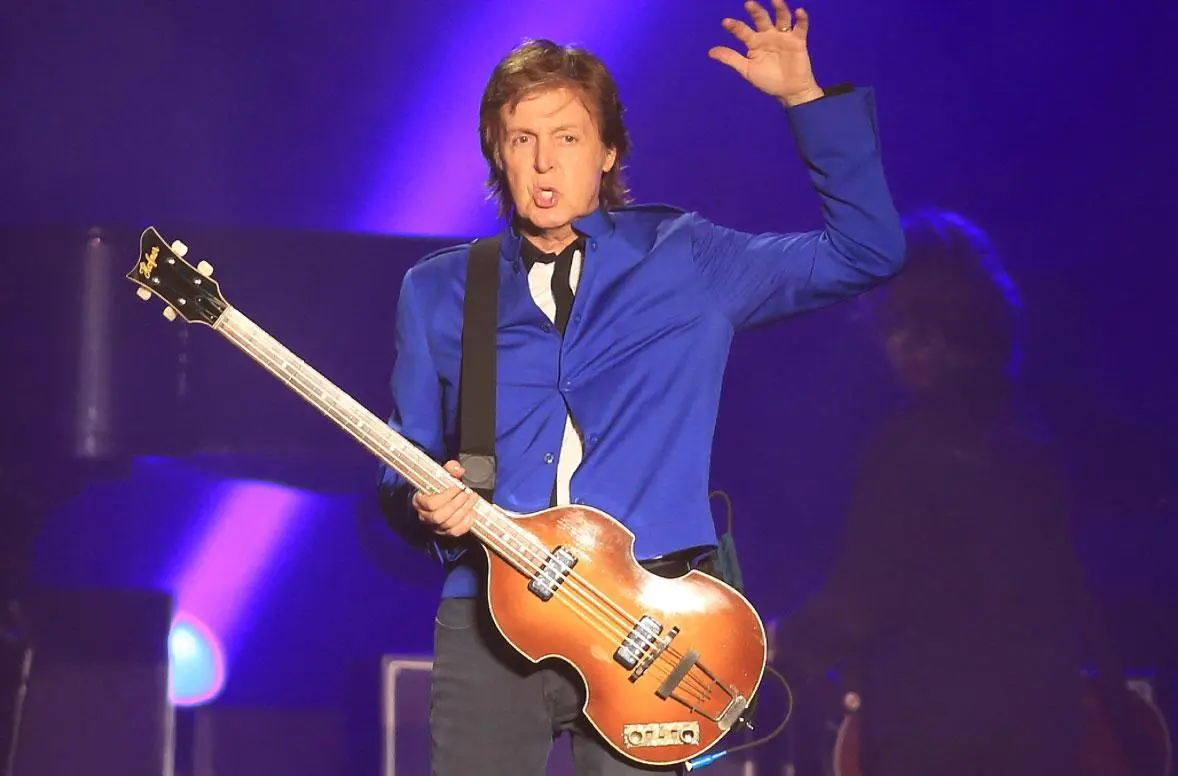 Paul McCartney no palco durante uma apresentação musical.