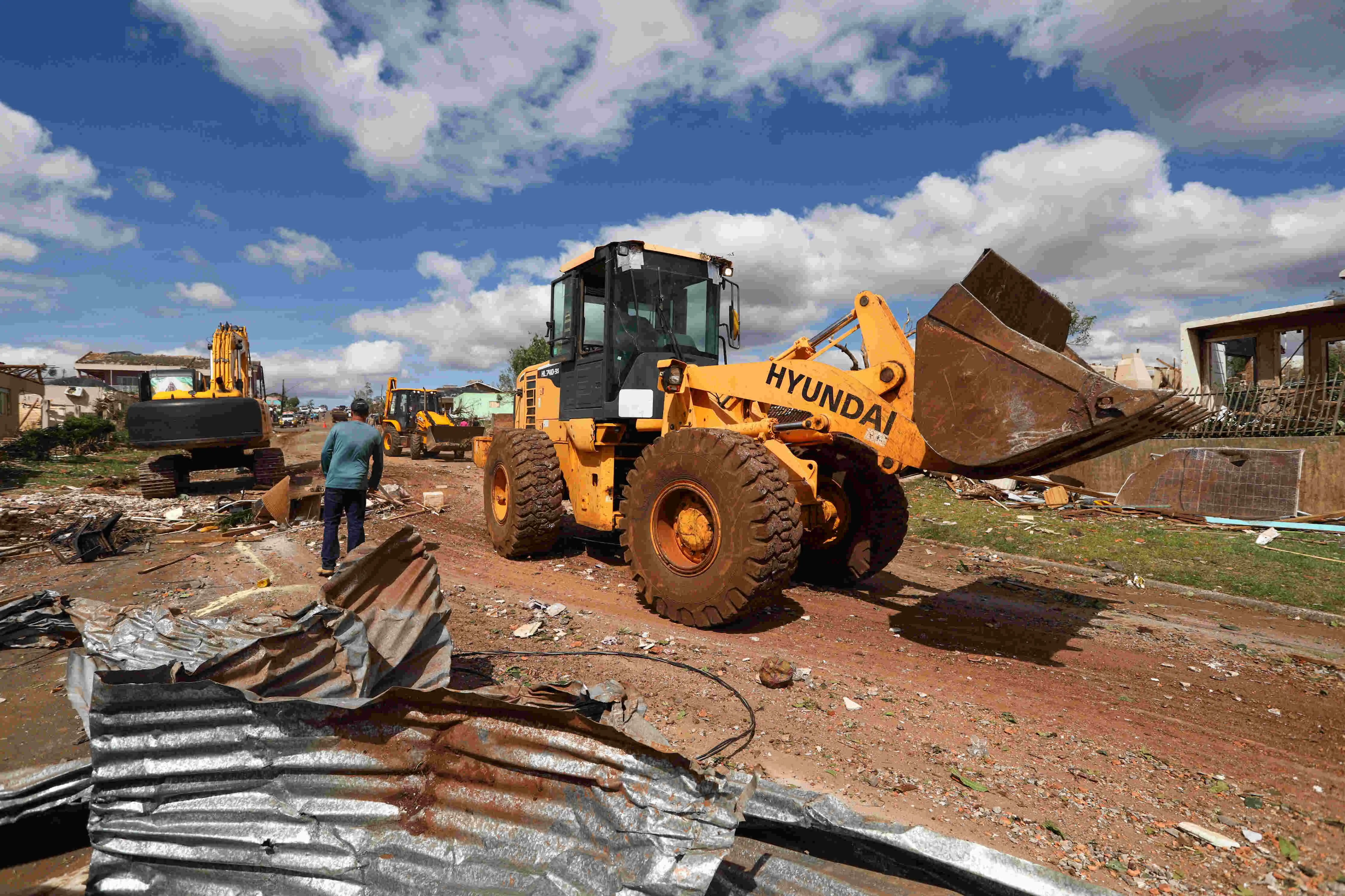 Na imagem uma retroescavadeira remove detritos causados pelo tornado com ventos.