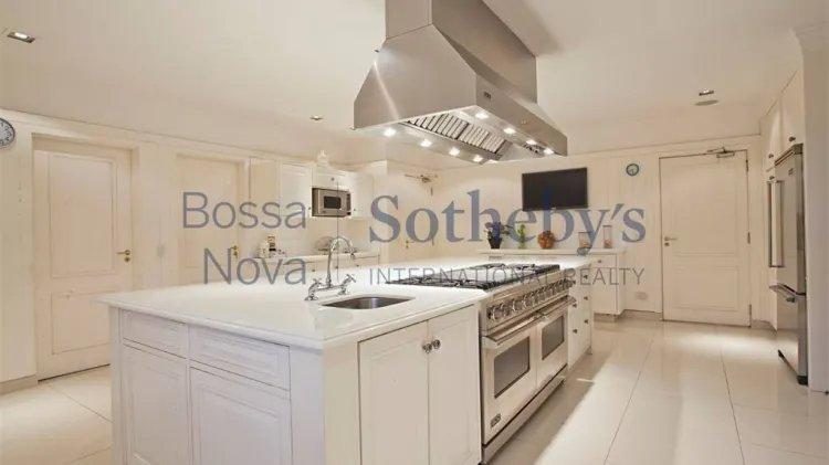 Imagem mostra uma cozinha com móveis todos brancos.