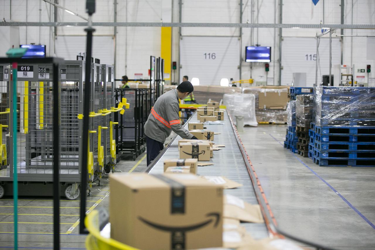 Trabalhadores empilhando caixas no centro de distribuição da Amazon.