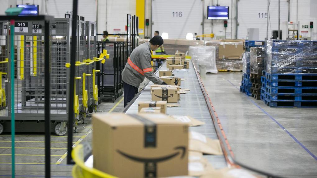 Trabalhadores empilhando caixas no centro de distribuição da Amazon.