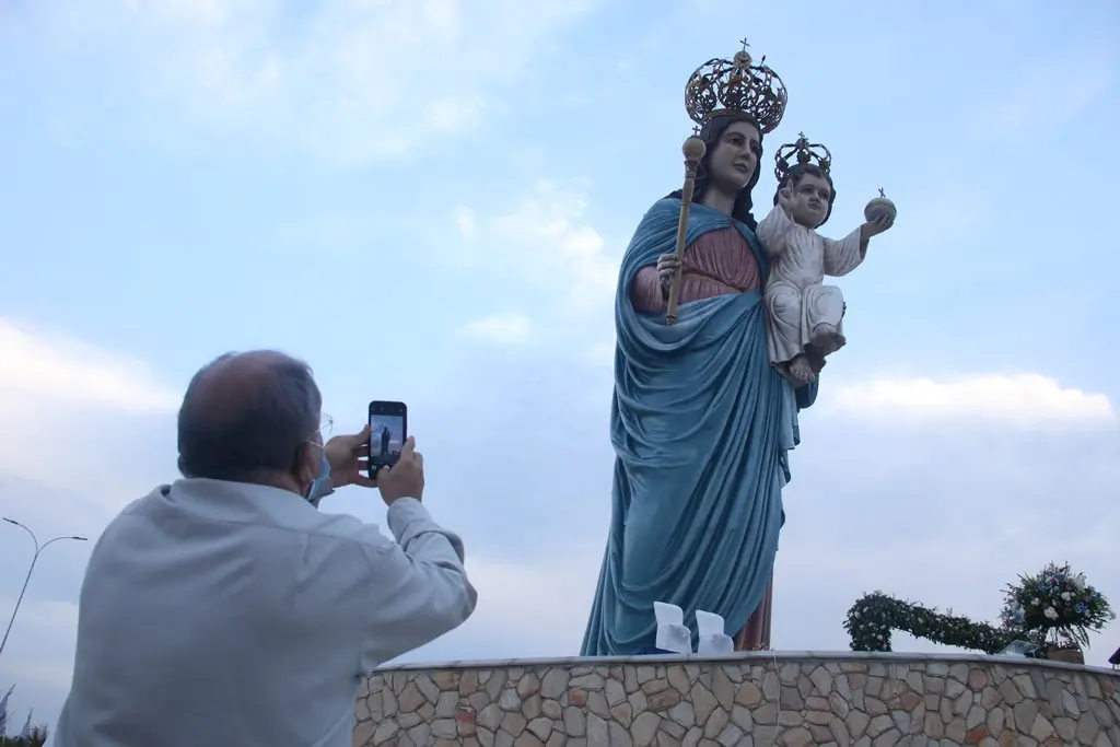 Imagem mostra homem de costas fotografando uma estátua grande de Nossa Senhora da Penha, em Campos Sales, no Ceará.