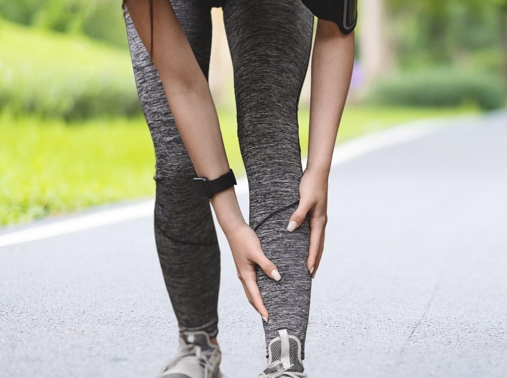 Corredora com a mão na canela.